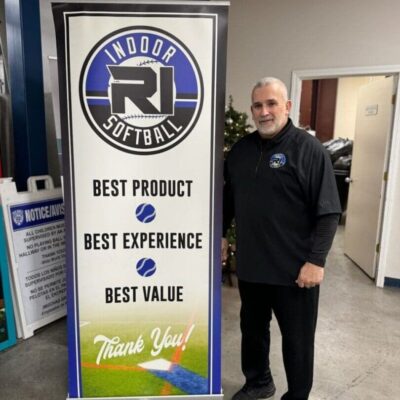 A man standing next to a sign that says indoor softball.