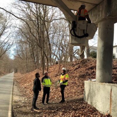 A group of people standing under the Cranston Bridge for inspections.