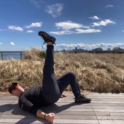 A man doing an exercise on a wooden boardwalk.