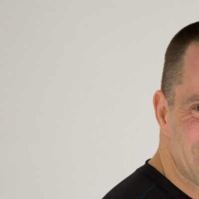 A fit man in a black t-shirt smiling.