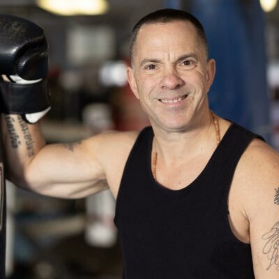 Smiling man boxing, tattooed arm.