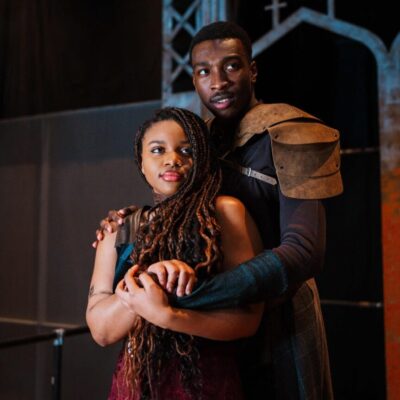 A man and woman posing for a picture on the URI Theatre stage.