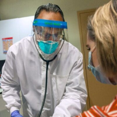 A man in a protective mask is examining a patient.