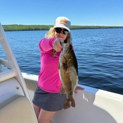 Woman holding large lake bass on boat.