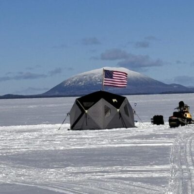 A tent on the ice with an american flag in the background.