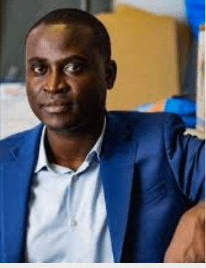 A man in a blue suit sitting in an office.