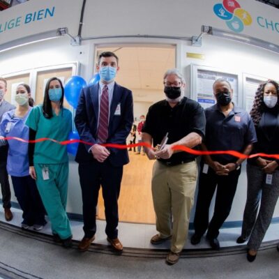A group of people standing in front of a ribbon cutting ceremony.