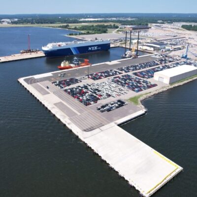 Here's an alt tag for the image: Automobiles at port, ship unloading.