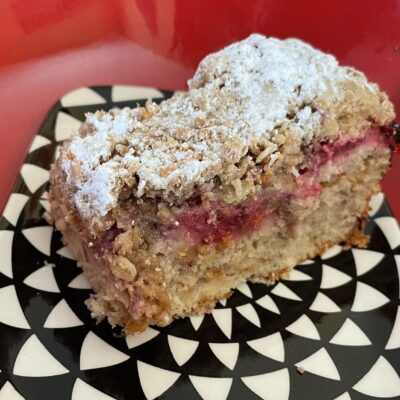 A piece of raspberry coffee cake on a black and white plate.