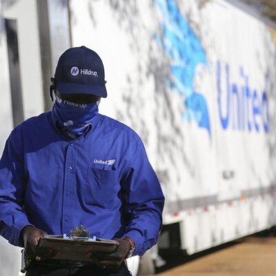 A man holding a clipboard in front of a truck.