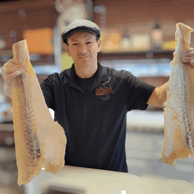 A man holding two large fish in his hands.
