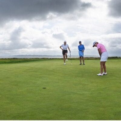 A group of hospice patients playing golf under a cloudy sky.