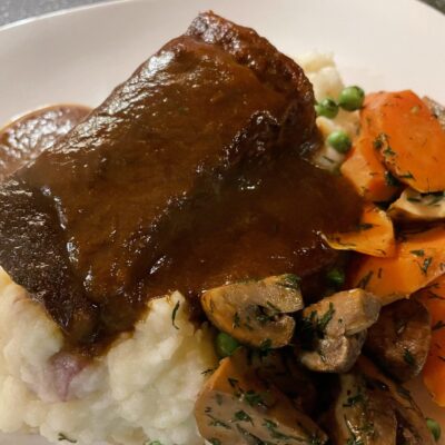 A plate with mashed potatoes, carrots and gravy.
