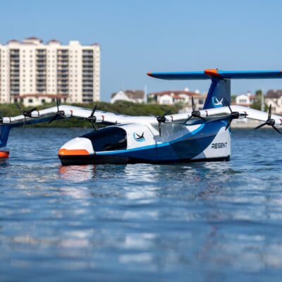 A toy airplane floating in the water with buildings in the background.