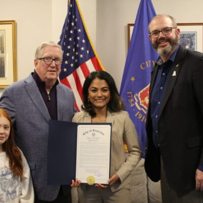 A group of people posing with a Dental Health Month certificate in front of an American flag.