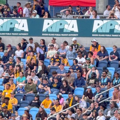 Crowd seated in a stadium, watching event.