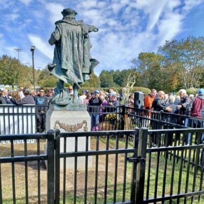 A crowd gathers around a statue of john f kennedy.
