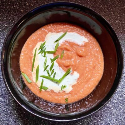 A bowl of tomato soup with sour cream and chives.