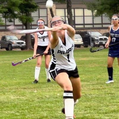 A field hockey player is trying to hit the ball.
