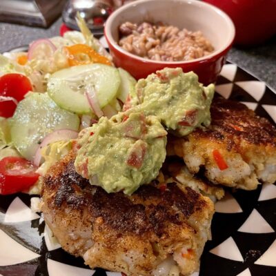 Crab cakes with guacamole and salad on a plate.
