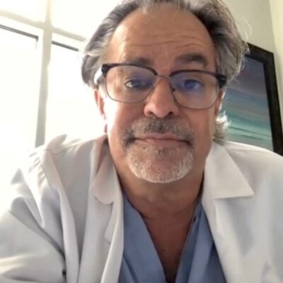 A man in a lab coat is sitting in front of a computer.