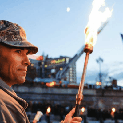A man holding a torch in front of an american flag.