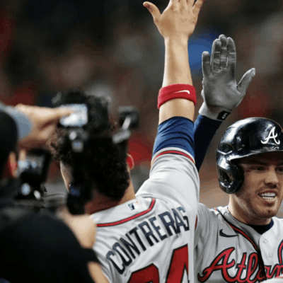 A baseball player is high fiving another player.