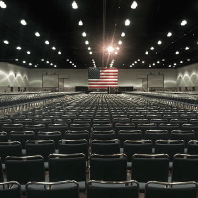 An empty room with rows of chairs and an american flag.