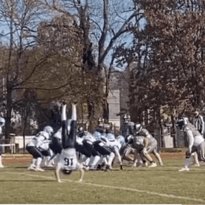 A football player is doing a handstand on the field.