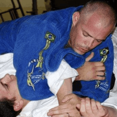 A man is doing a jiu jitsu choke on another man.