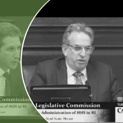 A man in a suit and tie sits in front of a green screen.