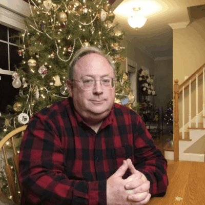 A man sitting at a table in front of a christmas tree.