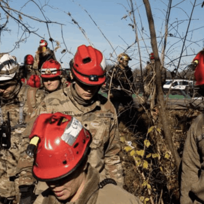 A group of soldiers wearing helmets in the woods.