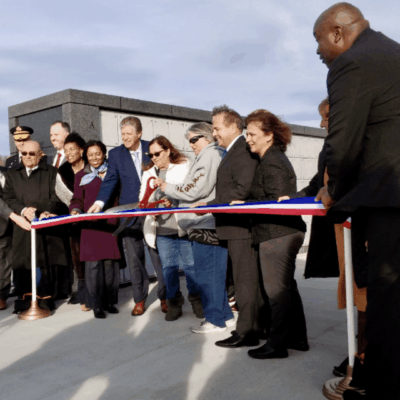 A group of people cutting a ribbon in front of a building.