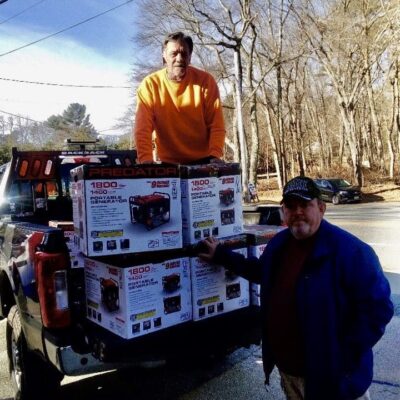 Two men standing on the back of a truck with boxes.