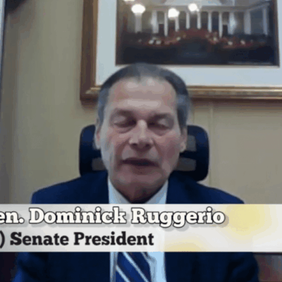 A man in a suit and tie is talking to the camera.