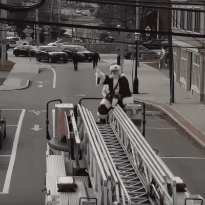 A fire truck on a street with a man on top of it.