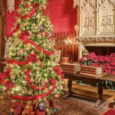 A christmas tree in an ornate room with stained glass windows.