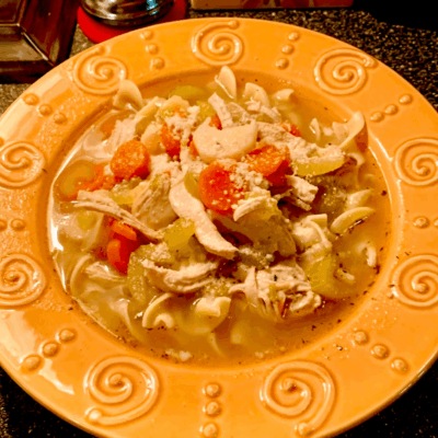 A bowl of chicken noodle soup on a table.