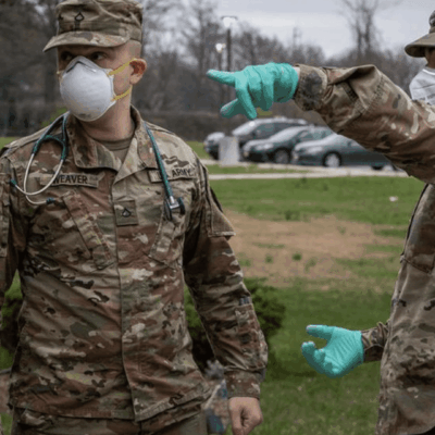 Two military men wearing face masks and gloves.