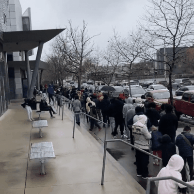 A group of people standing in a line outside of a building.