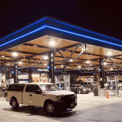 Two cars parked at a gas station at night.