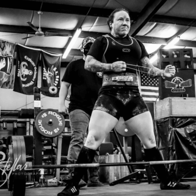 A man lifting a barbell in a gym.