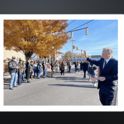 A man in a suit is waving to a crowd of people.