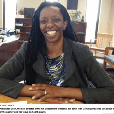 A woman with dreadlocks smiling at a desk.