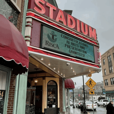 The front of a theater with a sign that says stadium.