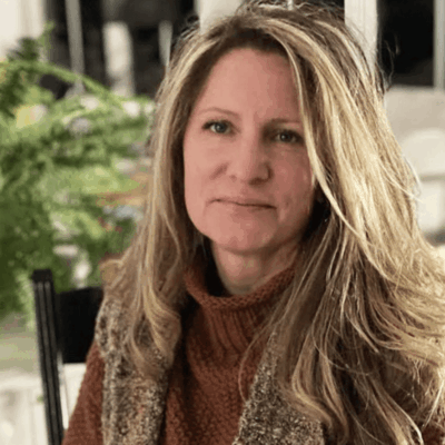 A woman in a brown sweater sitting in a chair.