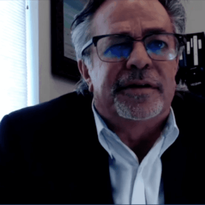 A man in glasses is sitting in front of a computer.