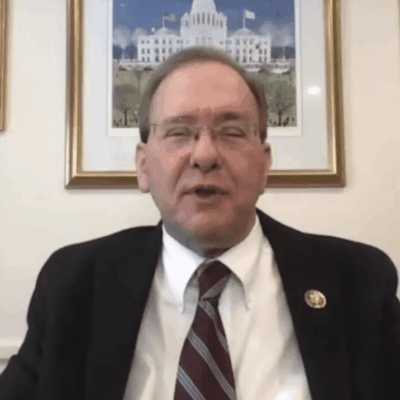 A man in a suit and tie sitting in front of a desk.