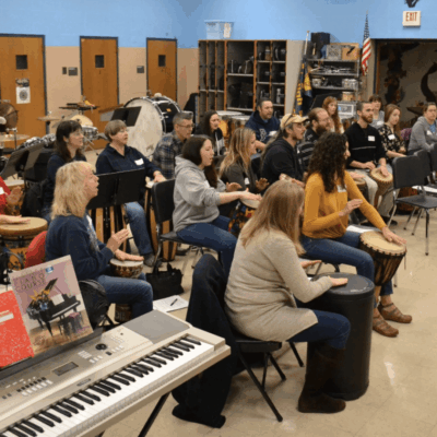 A group of people sitting in a classroom with music instruments.